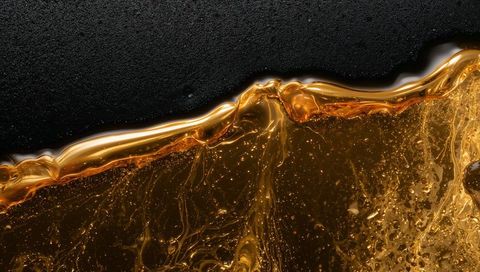 Flowing Amber-Gold Syrup Gliding Over Matte Black Surface Macro Texture and Bubbles