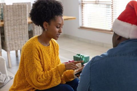 African american couple sharing tablet during cozy holiday gift exchange at home