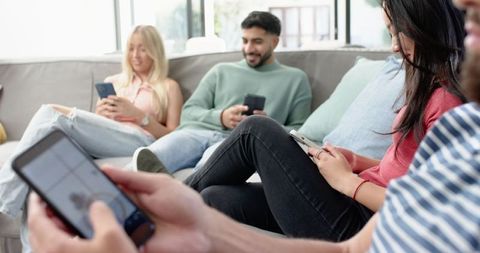 Friends Relaxing on Sofa with Smartphones in Bright Modern Living Room
