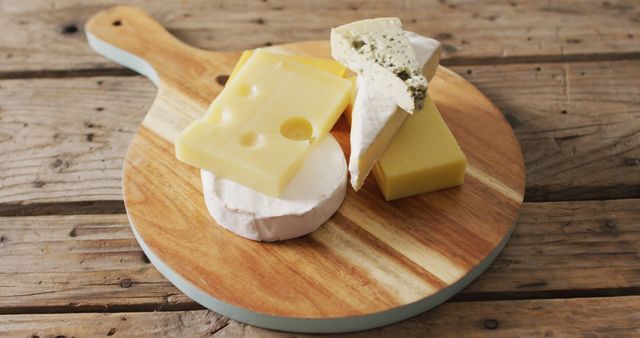 Image of assorted hard and soft cheeses on wooden chopping board and rustic table, with copy space. quality, tasty light food snack.