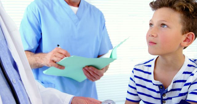 Boy participating in medical examination while nurse takes notes. Useful for illustrating healthcare themes, pediatric care, medical consultations, and clinical environments.