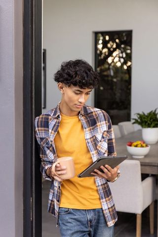 Young man relaxing with tablet and coffee in modern home