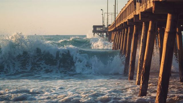 Sunset waves splashing against wooden pier