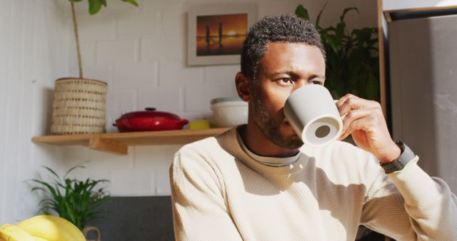 Happy african american man standing in kitchen, drinking coffee - Download Free Stock Photos Pikwizard.com