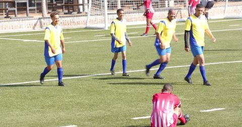Soccer Team Celebrating Goal on Field in Yellow Jerseys
