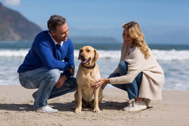 Mature couple petting their dog on the beach