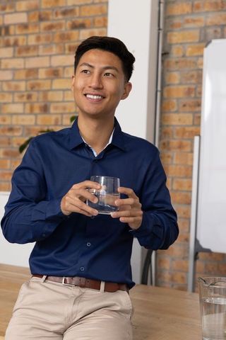 Smiling young professional in modern office with glass of water