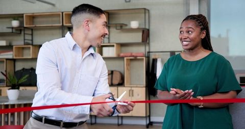 Diverse colleagues at office ribbon cutting ceremony celebrating new beginning
