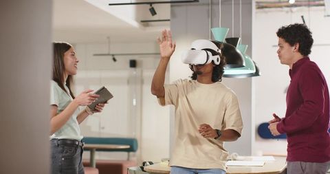 African American Colleague Exploring VR Headset While Diverse Team Collaborates in Coworking Space
