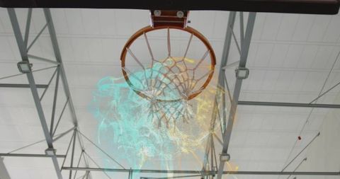 Overhead basketball hoop with cyan and yellow smoke swirling inside industrial gymnasium
