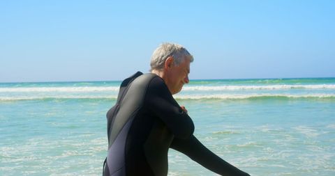 Senior Surfer Preparing on Sunlit Beach in Wetsuit