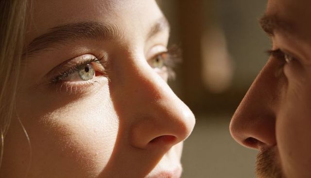 Closeup romantic gaze between couple in warm natural light, intimate close moment at home