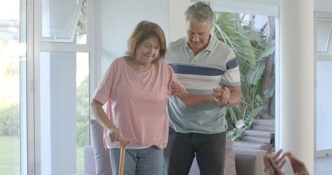 Senior Couple Supporting Each Other with Walking Cane at Home
