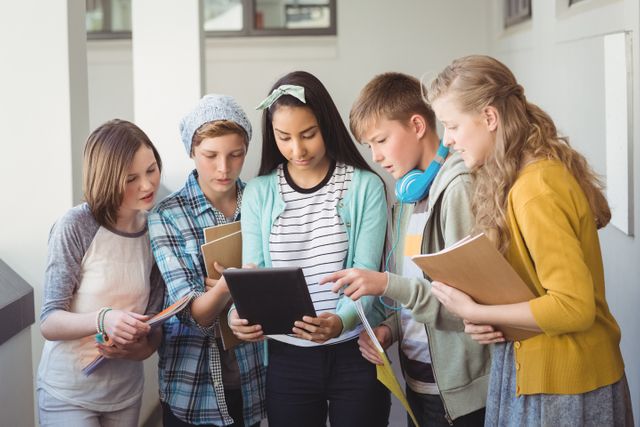 Group of diverse school friends gathered in a corridor, using a digital tablet for studying and collaboration. Ideal for educational content, technology in education, teamwork, and youth lifestyle themes.