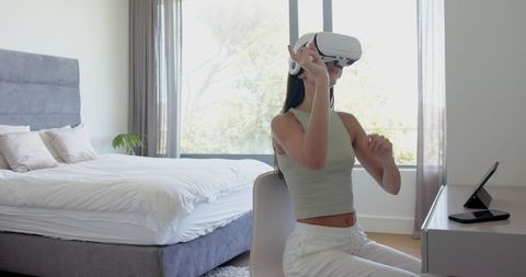 Young Woman Engaging with Virtual Reality in Modern Bedroom