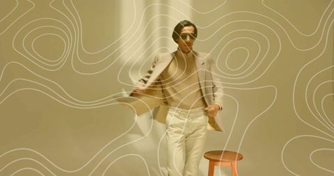 Stylish asian male model in beige fashion ensemble in minimalist studio