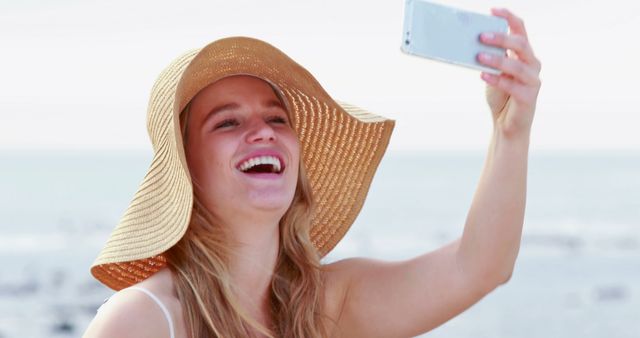 Young Woman Enjoying Beach Day Taking Selfie in Sun Hat - Download Free Stock Images Pikwizard.com