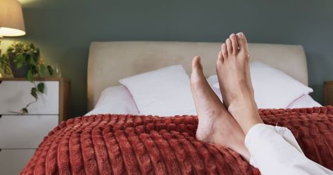 Barefoot Couple Relaxing Under Cozy Red Blanket in Bedroom