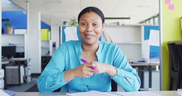 Confident Businesswoman in Office Setting Holds Pen and Smiles - Download Free Stock Images Pikwizard.com