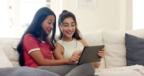 Diverse Female Friends Enjoying Tablet Time on Comfortable Sofa