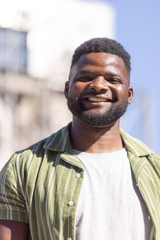 African american man smiling and standing in green striped shirt — urban casual sunny portrait