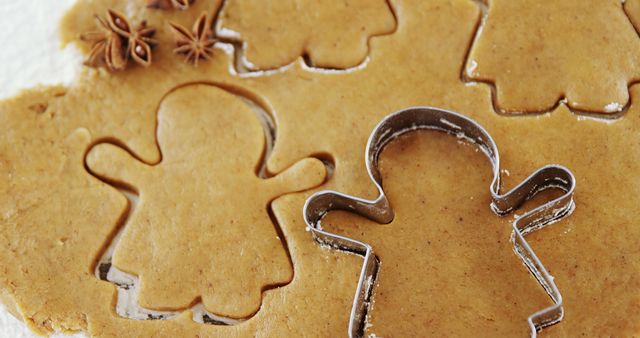 This cozy scene shows cookie cutters used to shape gingerbread dough, perfect for holiday baking and festive traditions. Ideal for use in articles, recipe blogs, magazines, and social media posts about holiday baking, cooking tutorials, festive activities, and family traditions.