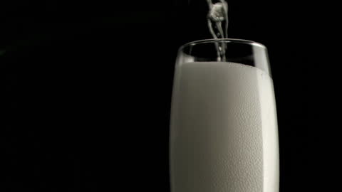 Chilled Champagne Pouring into Flute on Black Background