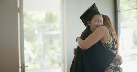 Mother embraces daughter in graduation celebration indoors