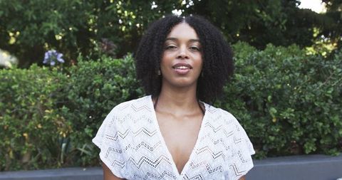 Confident african american woman standing in garden wearing white lacy blouse