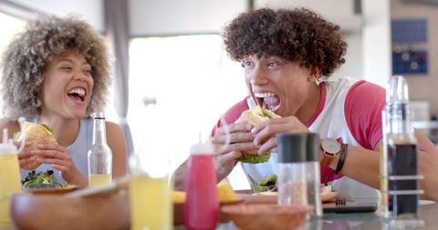 Diverse Friends Laughing and Eating Burgers at Home Gathering