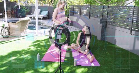 Fitness coach filming outdoor yoga stretching on pink mats by pool with ring light