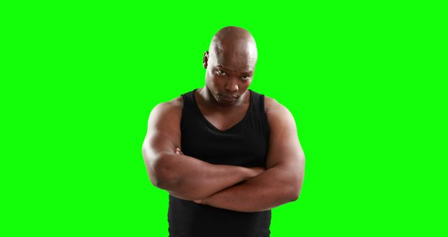 Confident man posing with arms crossed against a vibrant green screen background. He appears determined and serious, perfect for projects requiring a strong, assertive figure. Ideal for use in advertisements, promotional materials, or social media posts emphasizing confidence, strength, and determination.