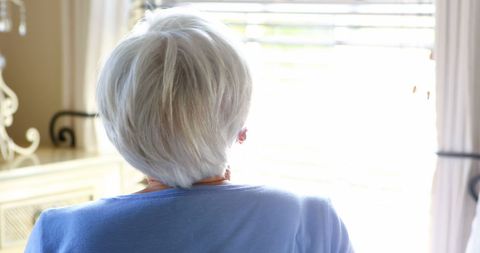 Elderly Woman Reflecting by Sunlit Window at Home
