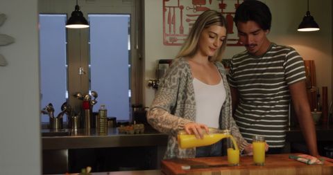 Couple Pouring Orange Juice in Home Kitchen