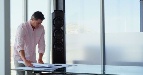 Businessman reviewing blueprints in modern office environment