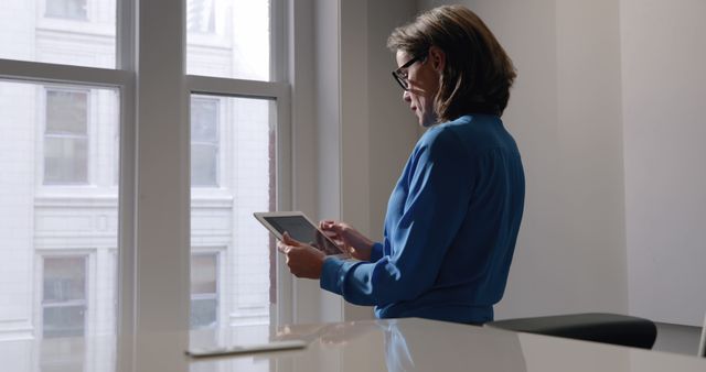 Professional Woman Working on Tablet Near Office Window - Download Free Stock Images Pikwizard.com