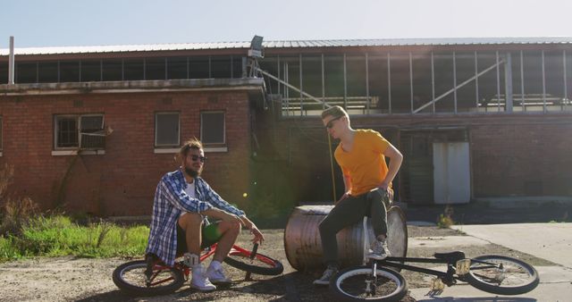 Two Young Men Taking a Break with Bicycles Near Industrial Building - Download Free Stock Images Pikwizard.com