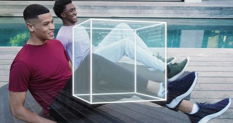Young men relaxing on poolside deck with holographic wireframe cube overlay, lifestyle