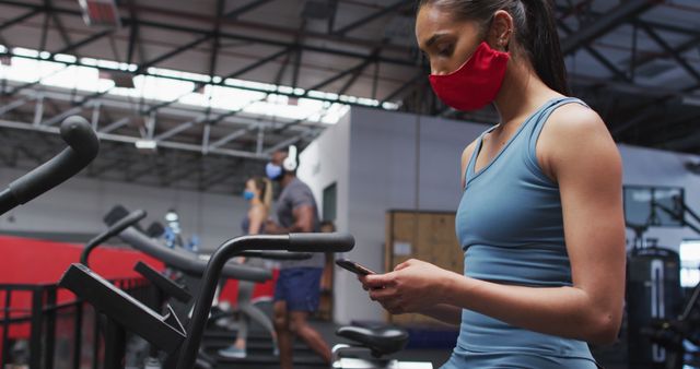 Woman Exercising at Gym with Face Mask While Using Smartphone - Download Free Stock Images Pikwizard.com