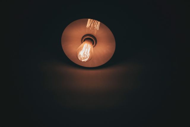This glowing vintage light bulb on a dark background emits a warm, ambient light, creating a cozy and nostalgic atmosphere. Ideal for illustrating concepts related to retro decor, lighting design, mood lighting, or minimalist aesthetics. Can be used in articles, blogs, and social media posts to add visual interest and emphasize themes of simplicity, warmth, and vintage style.