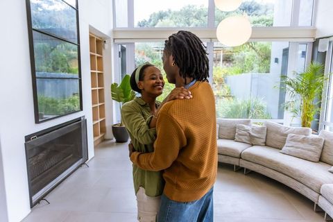 African american couple embracing in modern living room with large windows