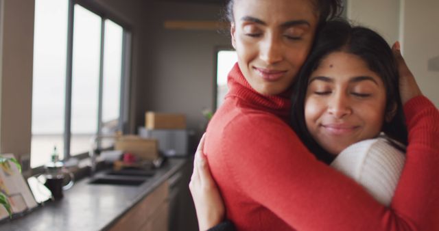 This depicts two sisters hugging in a kitchen, capturing a moment of emotional connection and warmth. Perfect for illustrating themes of family bonding, sibling love, and home life. Ideal for use in family-oriented advertisements, domestic settings, and lifestyle blogs.