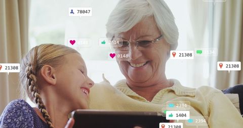Grandmother and granddaughter sharing tablet time with social media graphics