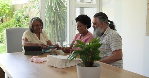 Senior Couple Online Shopping with Young Woman at Home