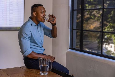 Professional break: man refreshing with water in modern conference room