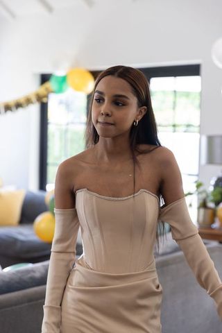 Young woman in beige gown during celebration in modern living room