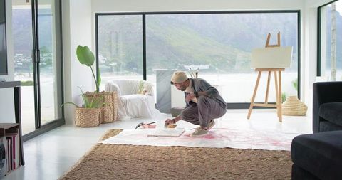 Indian artist painting in bright coastal living room studio with easel and natural light