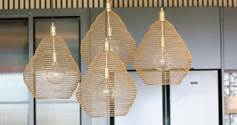 Hanging woven brass pendant lights forming sculptural cluster in modern lobby