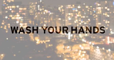 Cityscape at night with wash your hands reminder text