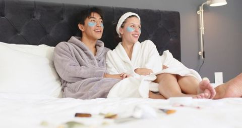 Couple enjoying at-home spa night wearing bathrobes and cooling under-eye patches